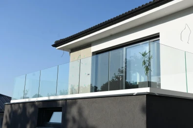Detail skleneného zábradlia na balkóne v Trenčíne – strieborný profil a číre sklo z nízkeho uhla